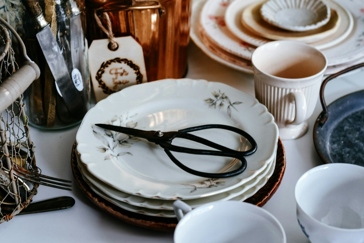 Stack of vintage plates with scissors and copper pot