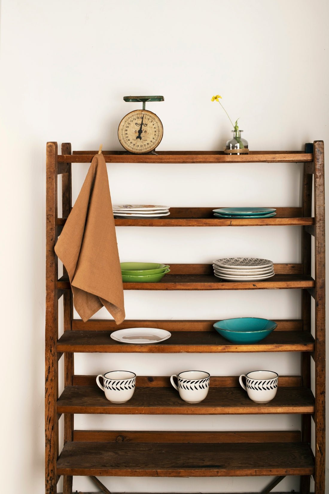 Wooden shelves hold dishes, cups, and a vintage scale