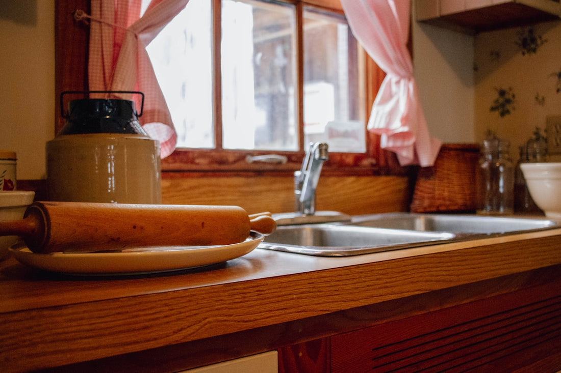 Wooden rolling pin on kitchen counter by sink and window