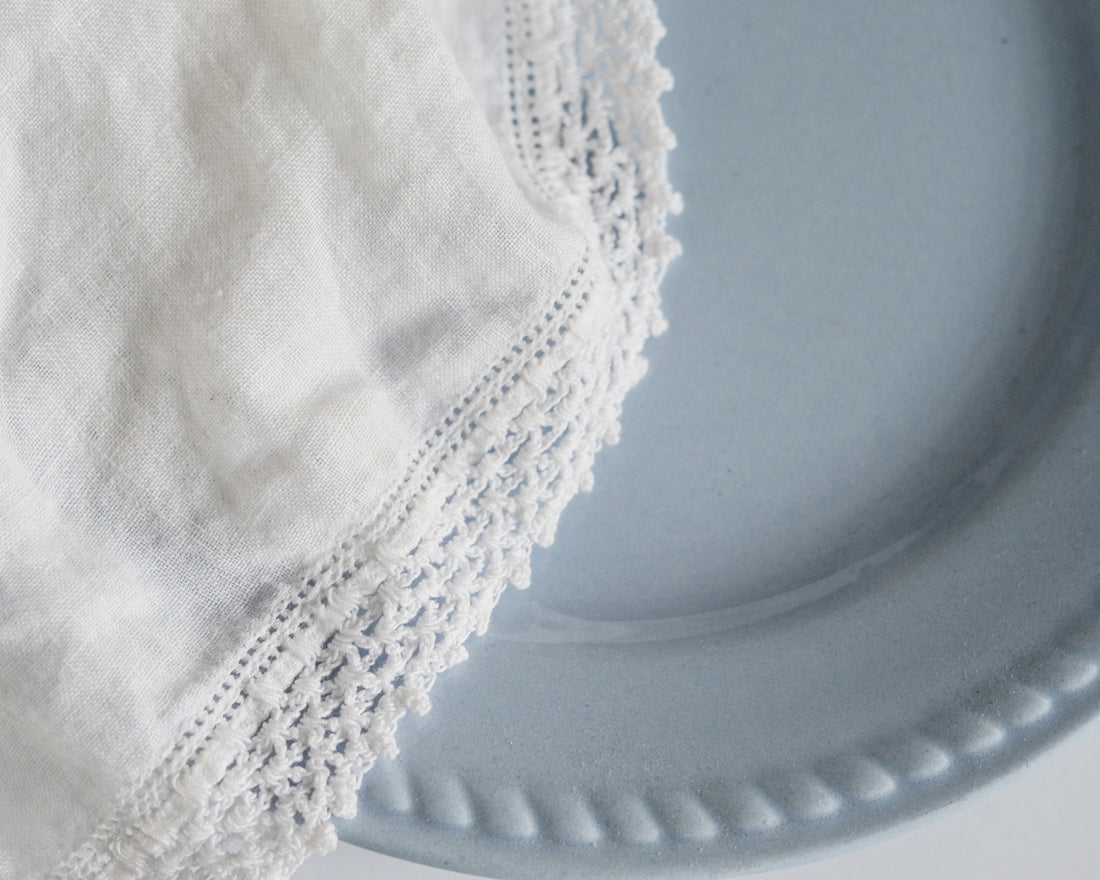 White lace fabric partially covers a light blue plate